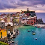 Vista panoramica di un pittoresco borgo marino italiano, con case colorate e mare blu.