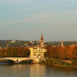 Panorama autunnale di una città italiana con foglie colorate e architettura storica.